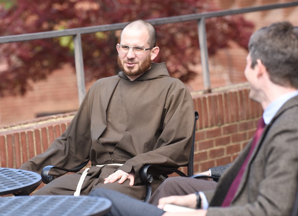 Man in religious robes sitting at table outside